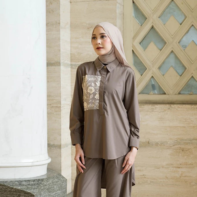 Woman wearing a brown outfit with floral embroidery by Tunique in an indoor setting