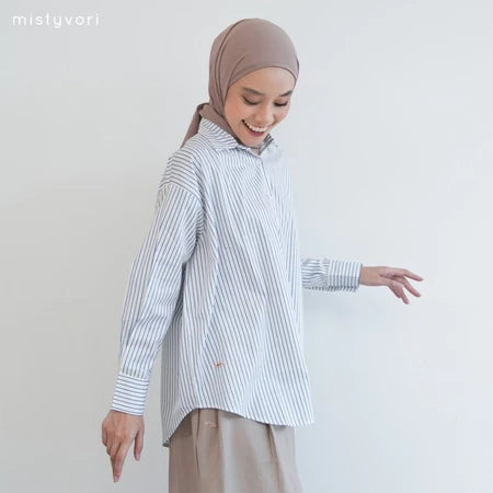 Woman wearing a blue striped shirt by Mistyvori and hijab on a plain background
