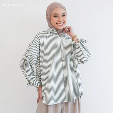 Woman wearing a green striped shirt by Mistyvori and hijab on a plain background