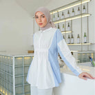 Woman wearing a white and blue striped shirt by Casa Elana with a hijab in an indoor setting.
