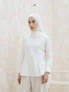 Woman wearing a white hijab and blouse by Swifter against a plain background