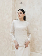 Woman wearing a light brown blouse by Swifter against a beige background