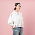 Person wearing a vanilla-colored jacket and jeans against a pink background with 'BWBYAZ' branding.