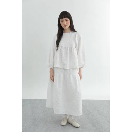 Woman wearing a white embossed top by Yestoday against a plain background