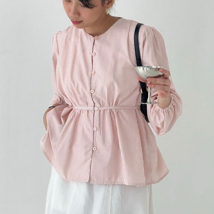 Person wearing a pink striped blouse by BWBYAZ holding a glass against a plain background