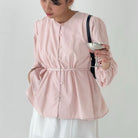 Person wearing a pink striped blouse by BWBYAZ holding a glass against a plain background