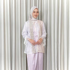 Woman wearing a white lace outer by Kartinis Label and hijab against a white curtain background