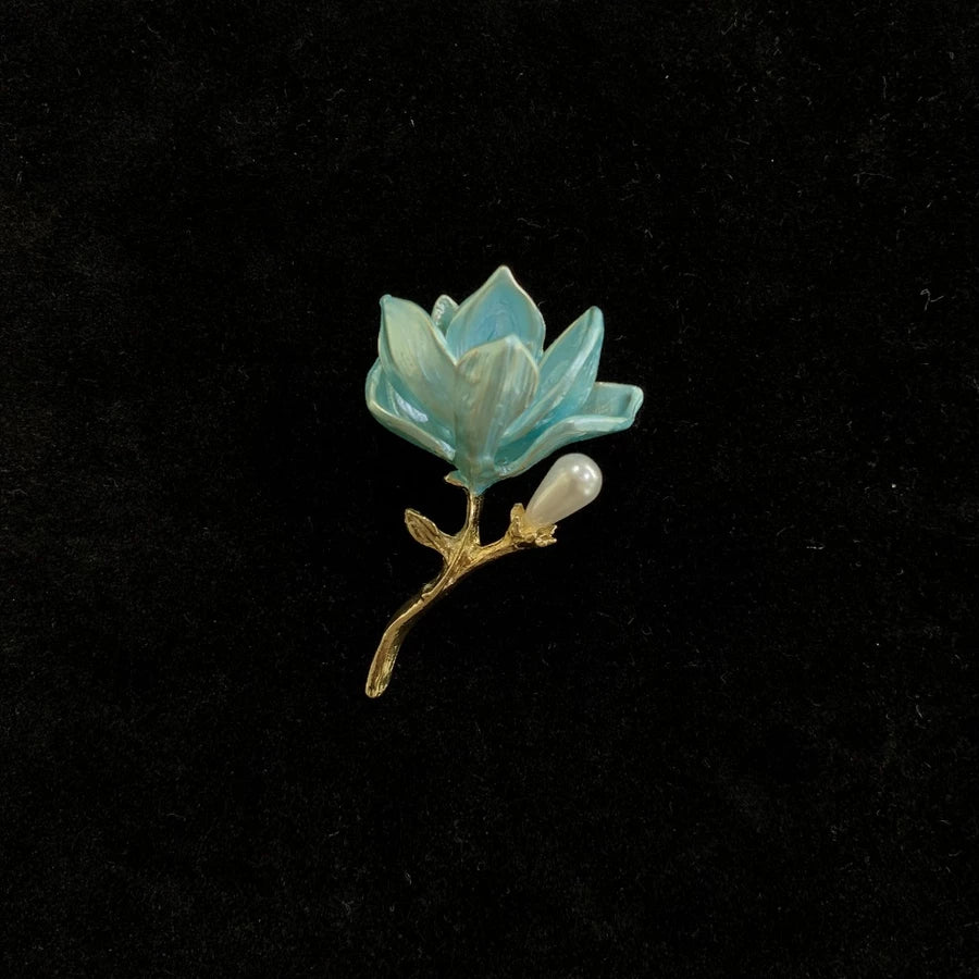 Teal blue lotus-shaped brooch by Holypeony with a pearl on a black background