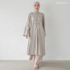 Seorang wanita memakai Fara Tunik, tunik berlengan panjang dengan material soft flanel dan memiliki aksen bunga, berwarna taupe.