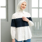 Woman wearing a white and navy shirt by Casa Elana with a hijab in a room with windows and candles.