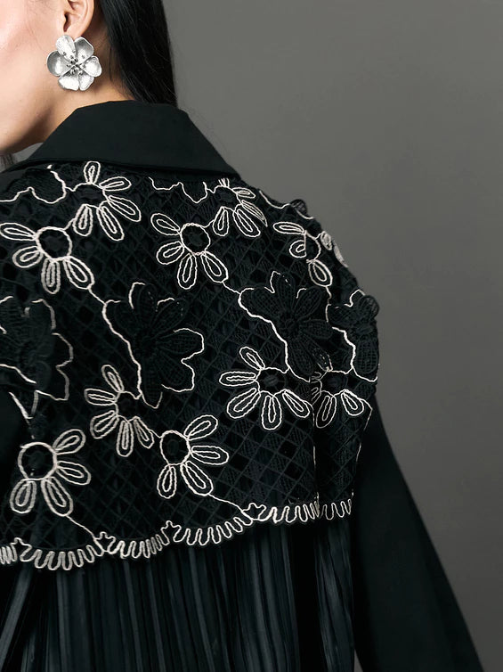 Black embroidered outerwear by Studio Tui with white floral patterns on a plain background
