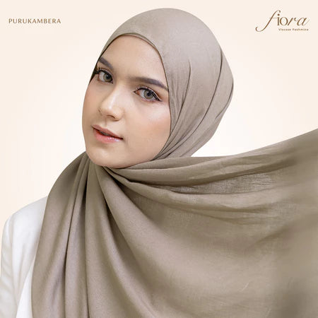 A woman wearing a beige pashmina viscose draped around her head, with the brand 'Puru Kambera' visible on the scarf.