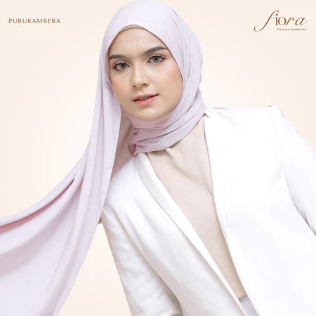A woman wearing a light pink pashmina viscose draped around her head, with the brand 'Puru Kambera' visible on the scarf.