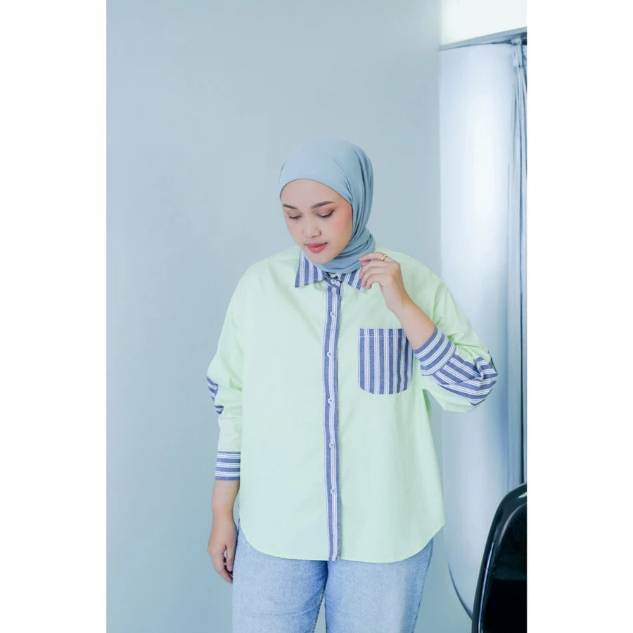 Woman wearing a light green shirt with striped sleeves and a matching hijab against a white background