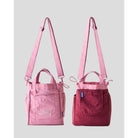 Women’s reversible tote bag by Muhajir Project featuring two looks in one design. One side comes in pink and a clean front pocket, while the other side shows a maroon with pink accents. Designed with adjustable shoulder straps, top handles, and side drawstring details for a practical and versatile everyday bag.