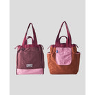 Reversible tote bag by Muhajir Project displayed in two sides, showing dual-color design with maroon and pink combination on one side and brown with pink pocket on the other. This versatile women’s bag features long shoulder straps, side drawstring details, and a functional front pocket, highlighting its practical and stylish two-in-one design.