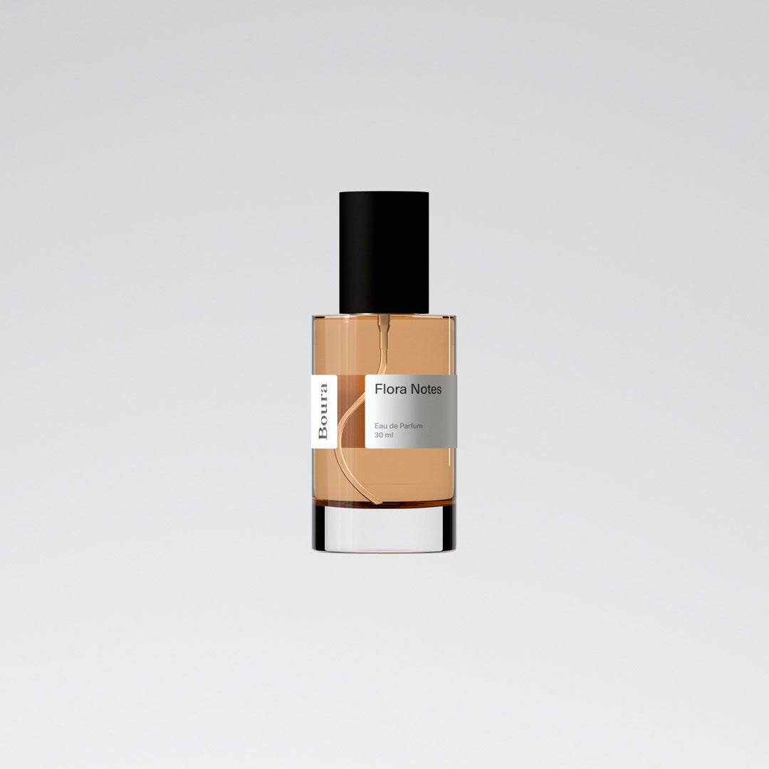 A bottle of 'Flora Notes' perfume with a beige liquid and black cap from Boura, presented against a white background.