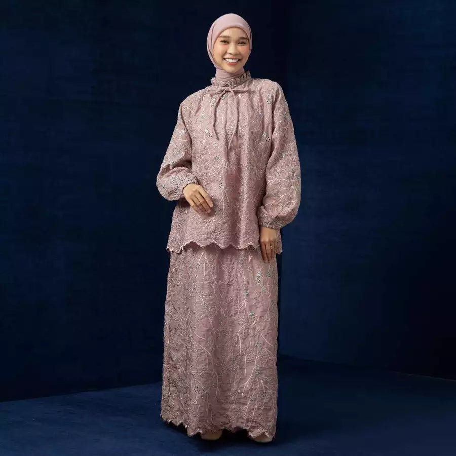 Woman wearing a pink traditional outfit by Lozy Hijab against a dark blue background