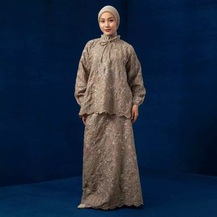 Woman wearing a beige traditional outfit by Lozy Hijab against a blue background