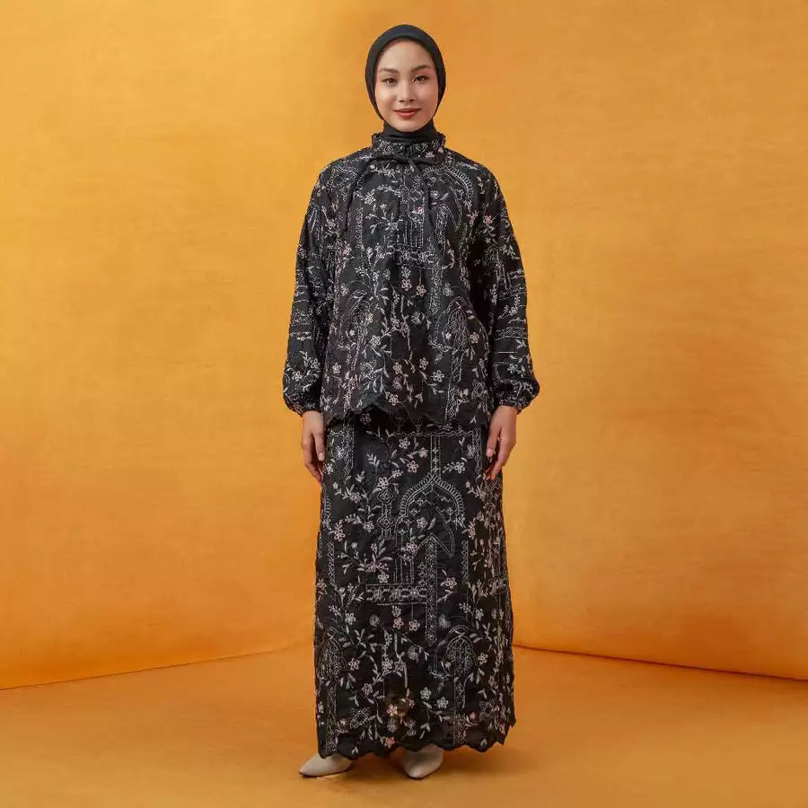 Person wearing a black floral patterned outfit by Lozy Hijab on an orange background