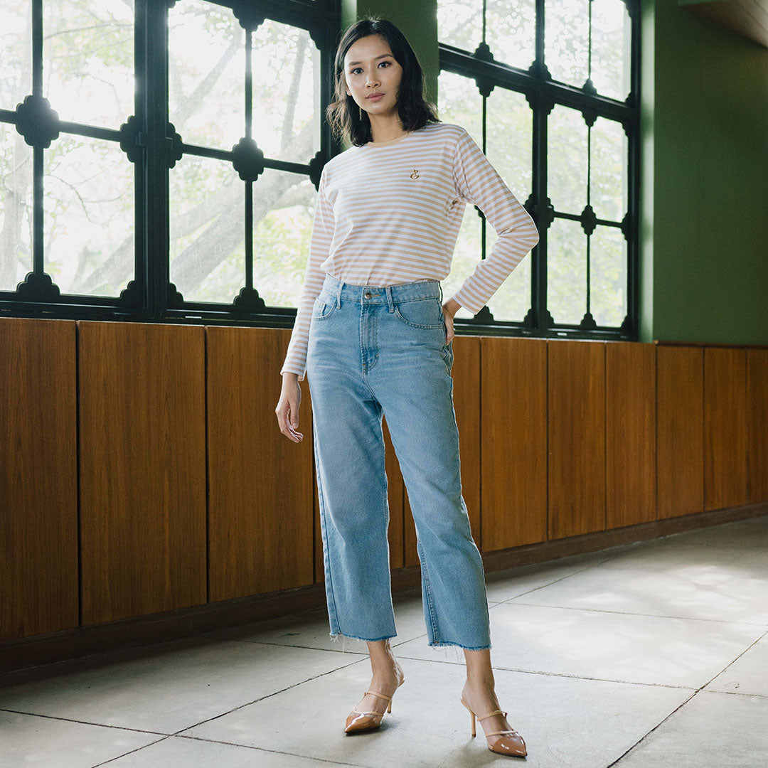 A woman standing in an indoor location with wooden paneling in the background, wearing light blue denim pants and a striped long-sleeve top.

Seorang wanita berdiri di dalam ruangan dengan panel kayu sebagai latar belakangnya, mengenakan celana denim biru muda dan atasan lengan panjang bergaris.