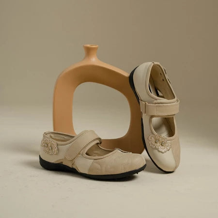 Pair of cream flat shoes with floral details by Dianable on a beige background