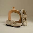 Pair of cream flat shoes with floral details by Dianable on a beige background