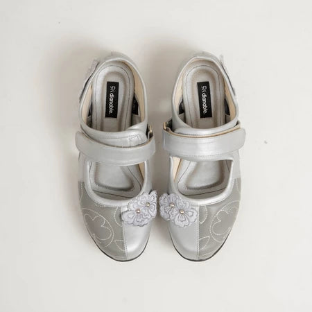 Pair of silver flat shoes with floral embellishments by Dianable on a white background