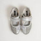 Pair of silver flat shoes with floral embellishments by Dianable on a white background