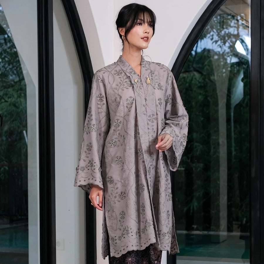 Woman wearing a gray women’s tunic by Holy Peony with subtle floral patterns, a loose silhouette, and wide sleeves. The tunic features a layered front detail and above-the-knee length, creating an elegant and flowy look.

Wanita mengenakan tunik wanita warna abu-abu dari Holy Peony dengan motif floral halus, potongan longgar, dan lengan lebar. Tunik memiliki detail layering di bagian depan dengan panjang di atas lutut, menciptakan tampilan elegan dan flowy.