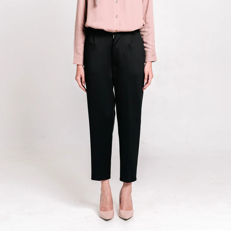 Person wearing black ankle pants from Atala Scarves and a light pink shirt on a white background