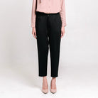 Person wearing black ankle pants from Atala Scarves and a light pink shirt on a white background
