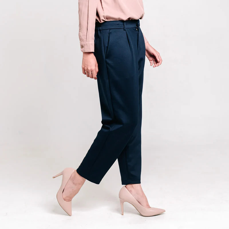Person wearing navy ankle pants from Atala Scarves and pink shoes on a light gray background