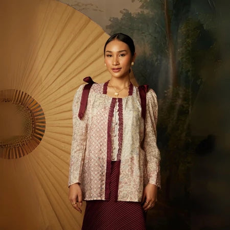 Woman wearing a traditional kebaya by Kartinis Label with a decorative and painting in the background