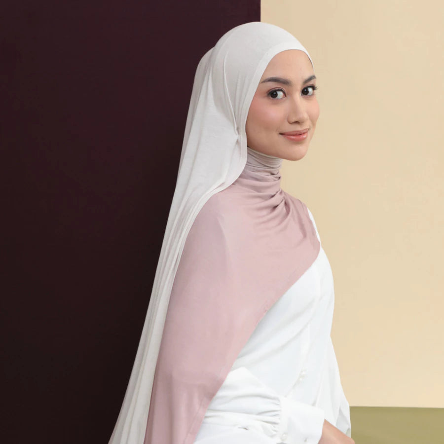 Woman wearing a white hijab shawl by Lozy Hijab and pink top against a two-tone background