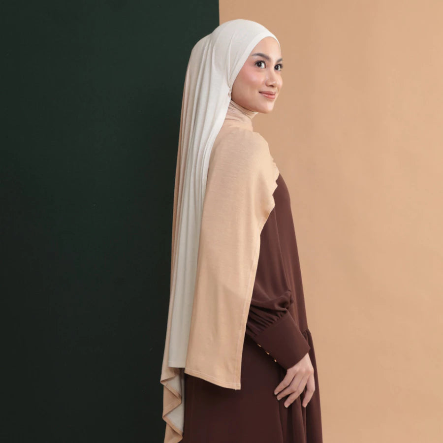 Woman wearing a cream hijab shawl by Lozy Hijab and two different colored tops against a gradient background