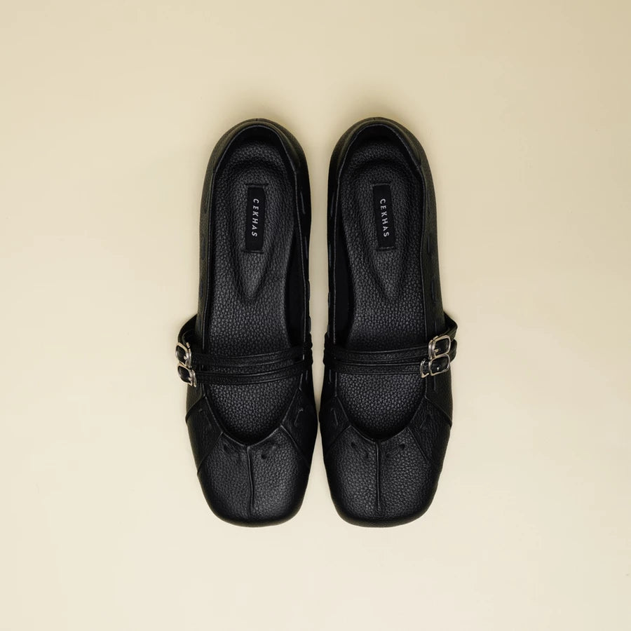 A pair of black pebbled leather Mary Jane flatshoes with silver-tone buckle straps by Cekhas, shown from a top-down view on a light beige background.