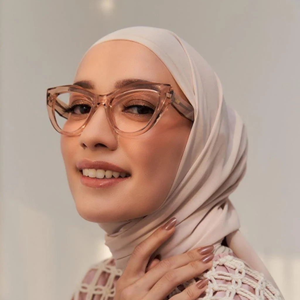 A woman wearing a headscarf and stylish glasses from HSF Eyewear with a cat-eye design in a champagne color frame.
