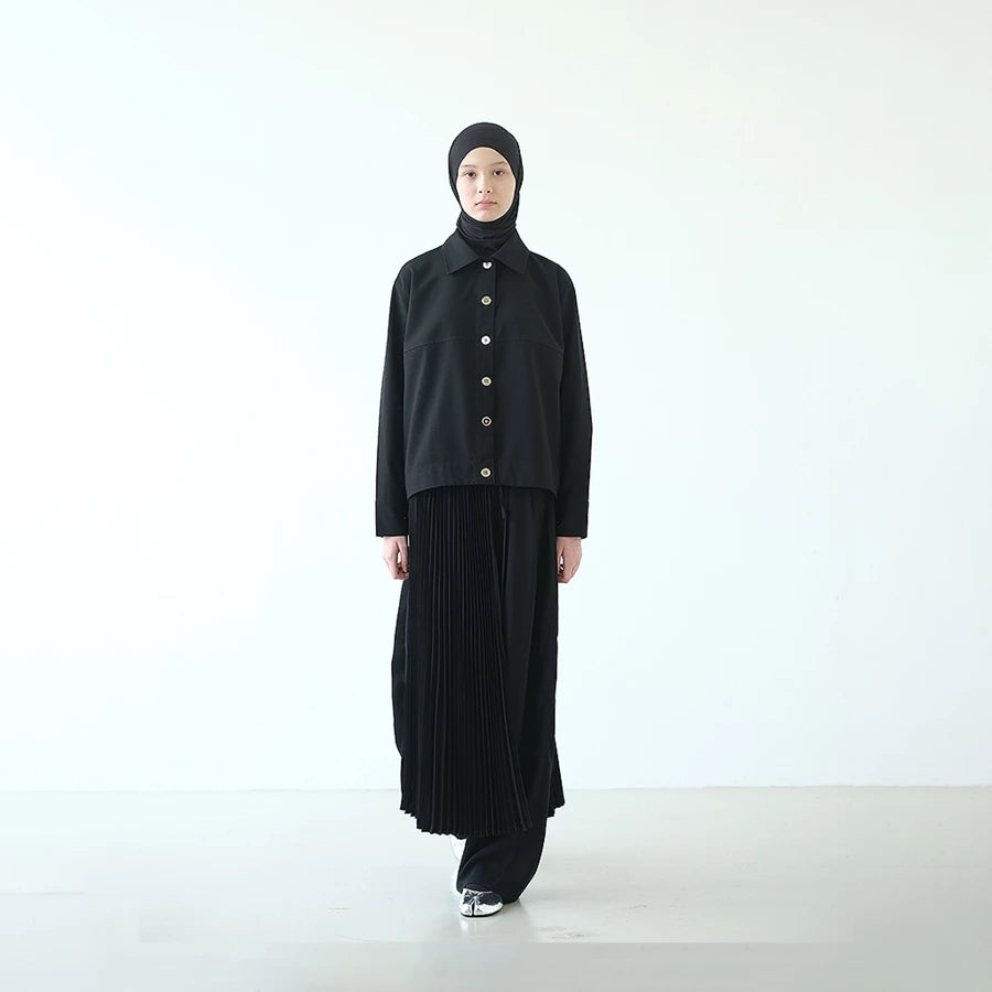Person wearing a black shirt by Rashawl and skirt with a hijab on a white background