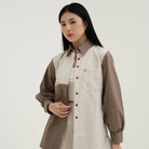 Woman wearing a two-tone blouse by Tunique with a neutral background