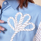 Blue and white striped shirt with a decorative bow design on the chest by Casa Elana.