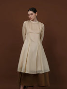 Seorang wanita memakai tunik berlengan panjang berwarna almond dari brand Kasa Heritage.