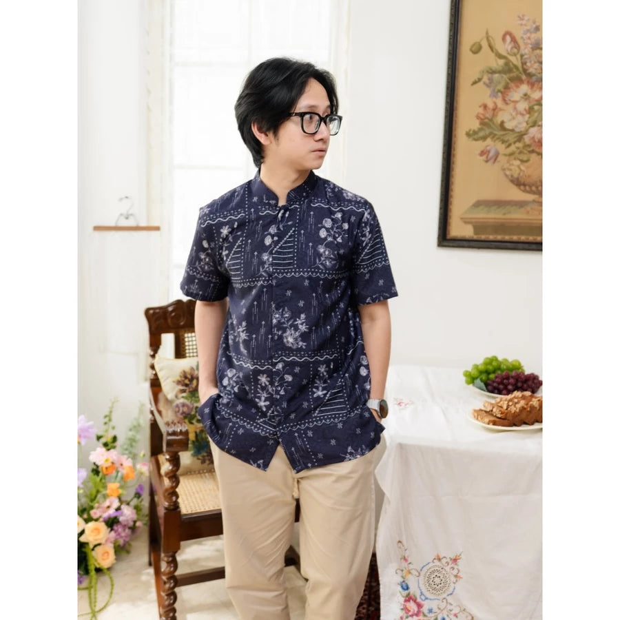Person wearing a navy patterned shirt by Haidee Orlin in a room with a table and decorative items.
