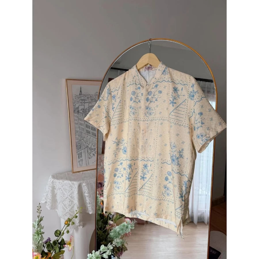 Yellow floral patterned shirt by Haidee Orlin on a hanger against a neutral wall with decor elements.