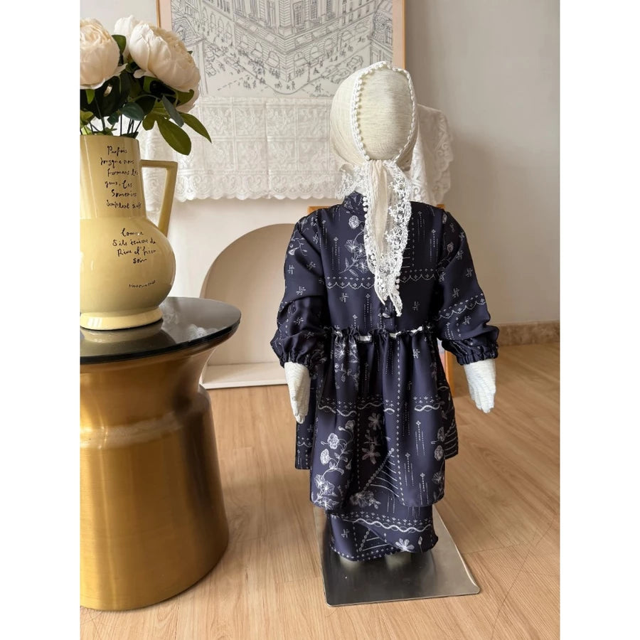 Mannequin wearing a navy floral dress by Haidee Orlin with white patterns on a wooden floor.