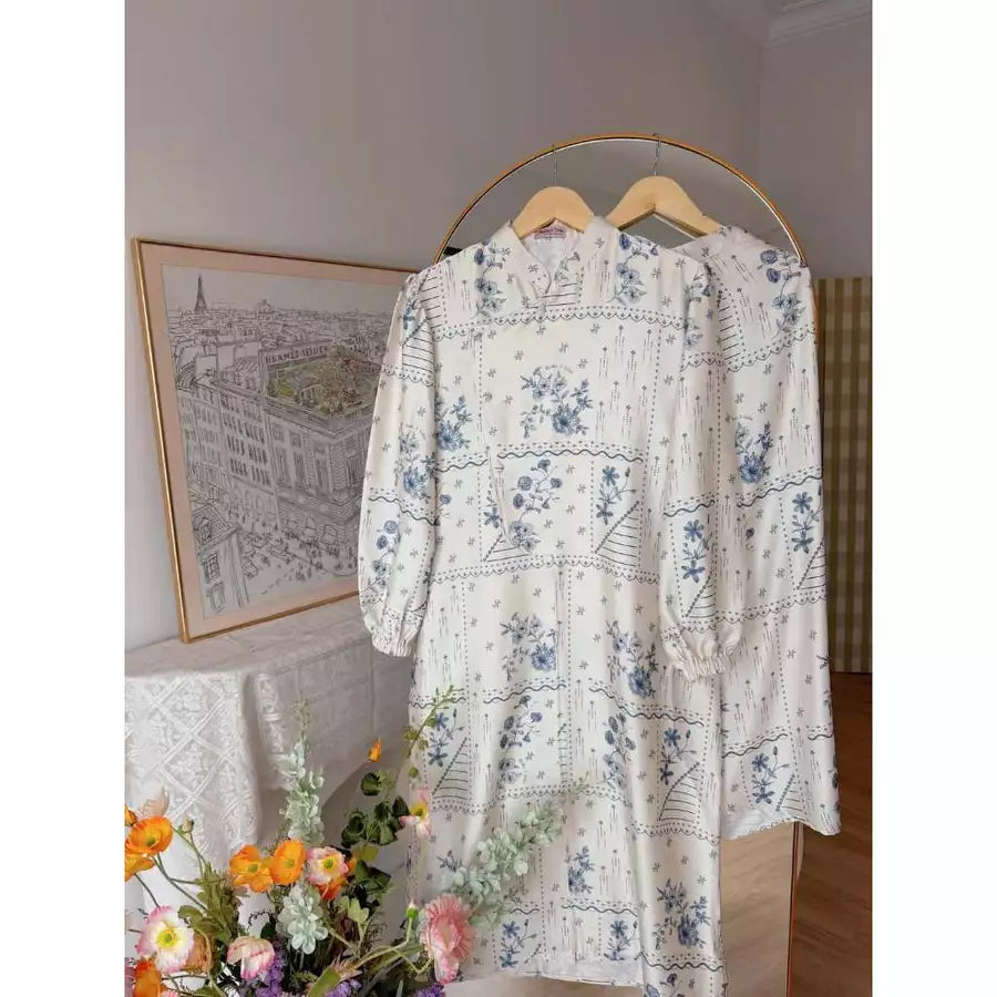 Cream blue floral tunic by Haidee Orlin on a hanger with a decorative background