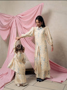 Woman and child in matching yellow floral tunic by Haidee Orlin standing in front of a pink curtain.