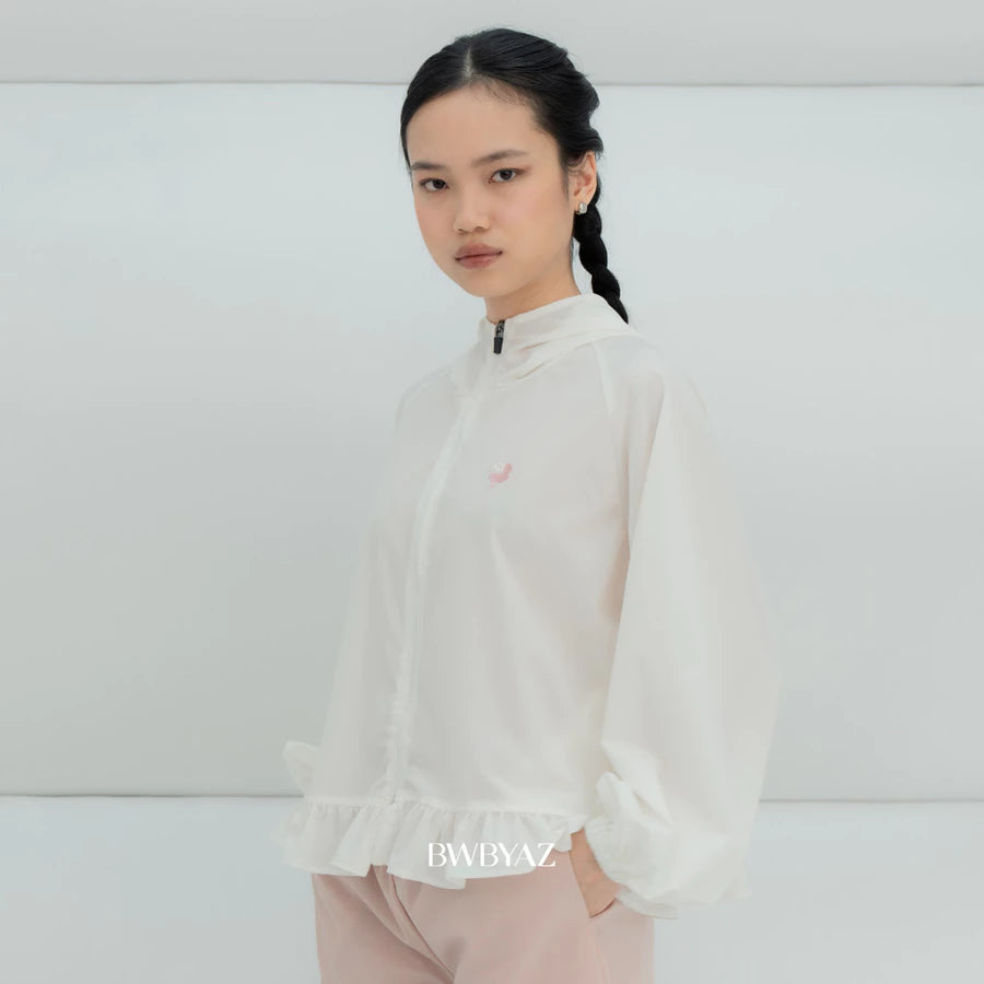 A model wearing a white lightweight zip-up windbreaker jacket by BWBYAZ with a small pink embroidered logo on the chest, paired with light pink pants, set against a minimalist white studio background.