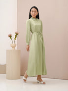 A woman wearing a green dress with long sleeves by Kasa Heritage, featuring a mandarin collar with detail and a detachable belt.