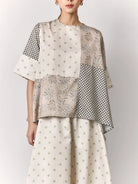 Woman wearing a two-piece outfit with a patterned blouse and skirt by Studio Tui on a white background